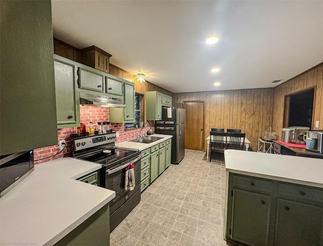 kitchen featuring appliances with stainless steel finishes, sink, green cabinets, and wooden walls