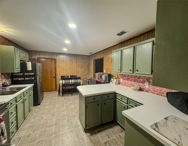 kitchen featuring green cabinets, appliances with stainless steel finishes, kitchen peninsula, and sink