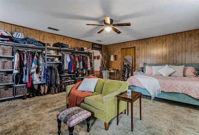 bedroom with ceiling fan, light colored carpet, and wooden walls