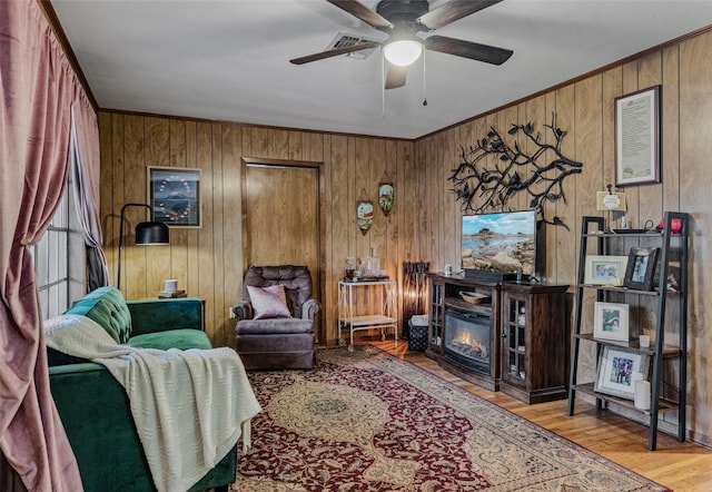 living room with crown molding, light hardwood / wood-style flooring, ceiling fan, and wood walls