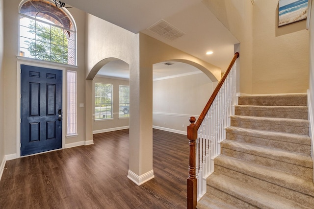 entryway featuring plenty of natural light, crown molding, dark wood-type flooring, and a high ceiling