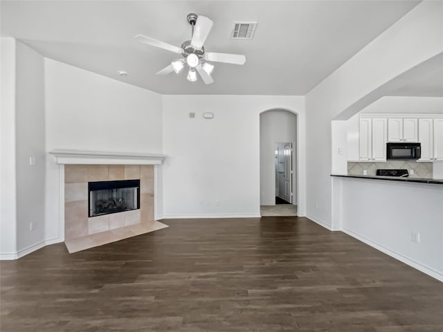 unfurnished living room featuring ceiling fan, a fireplace, and dark hardwood / wood-style floors