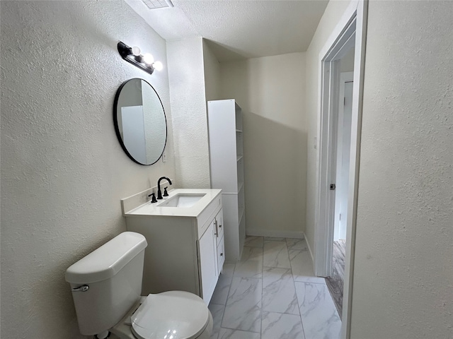 bathroom featuring toilet, vanity, and a textured ceiling