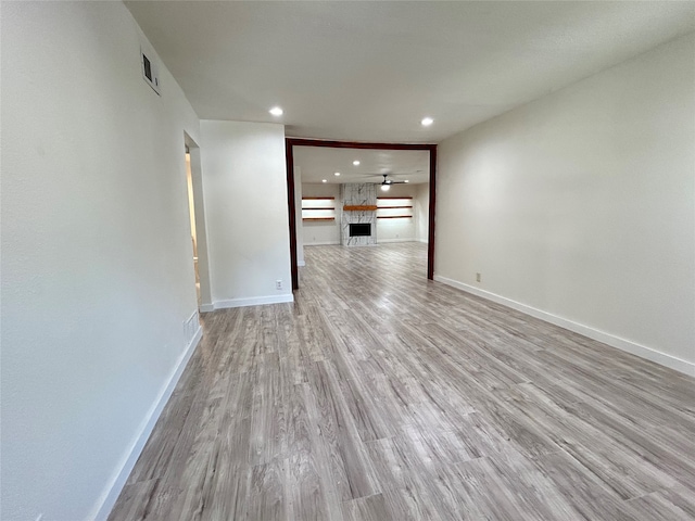 unfurnished living room featuring a fireplace, ceiling fan, and light hardwood / wood-style floors