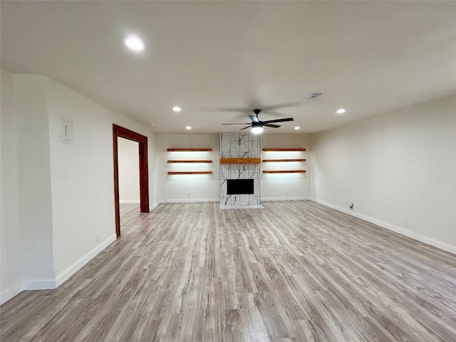 unfurnished living room with a fireplace, ceiling fan, and light hardwood / wood-style flooring