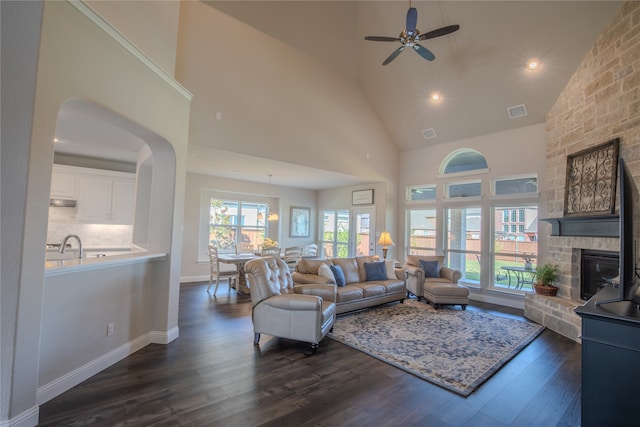 living room with a healthy amount of sunlight, a stone fireplace, dark hardwood / wood-style floors, and ceiling fan