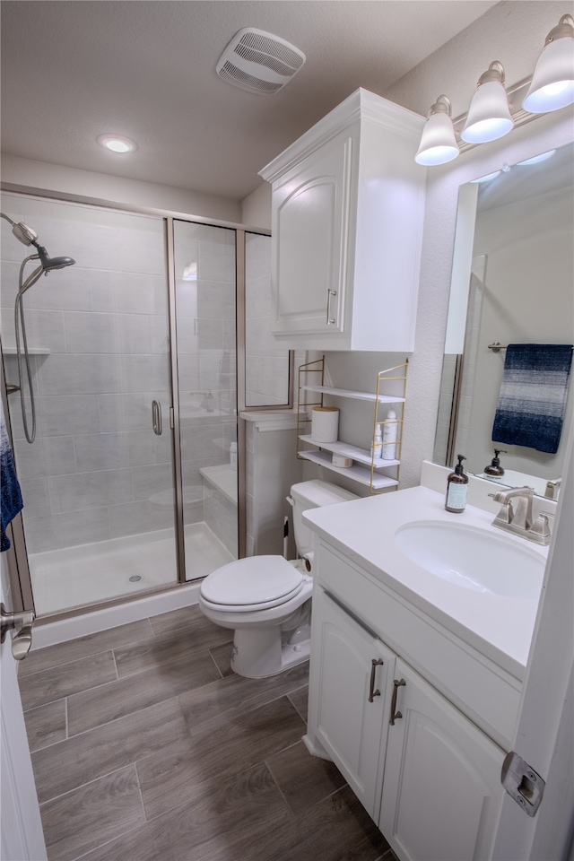 bathroom with a shower with door, vanity, and toilet