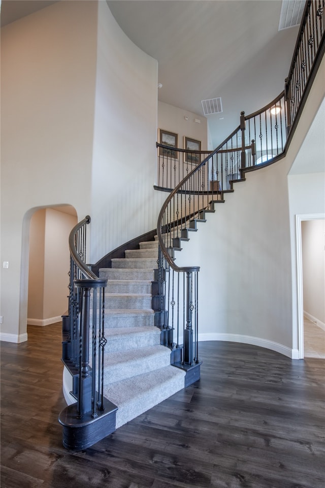 stairs featuring wood-type flooring and a towering ceiling