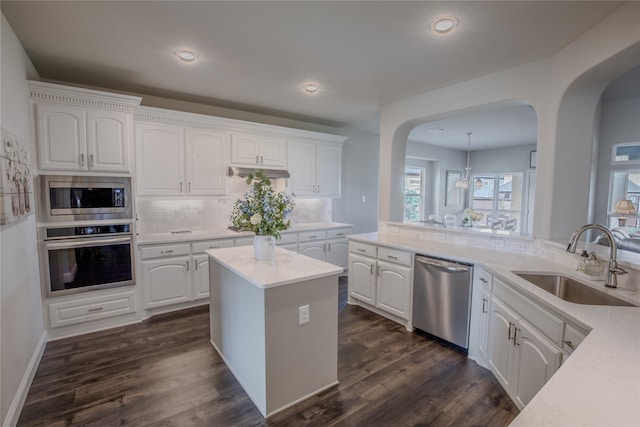 kitchen featuring white cabinets, hanging light fixtures, sink, stainless steel appliances, and dark hardwood / wood-style floors