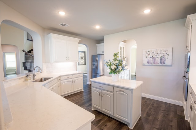 kitchen with white cabinets, sink, kitchen peninsula, dark wood-type flooring, and stainless steel appliances