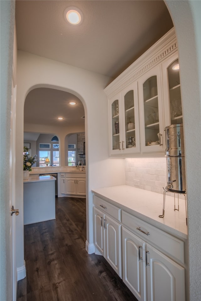 bar featuring backsplash, white cabinetry, sink, and dark wood-type flooring