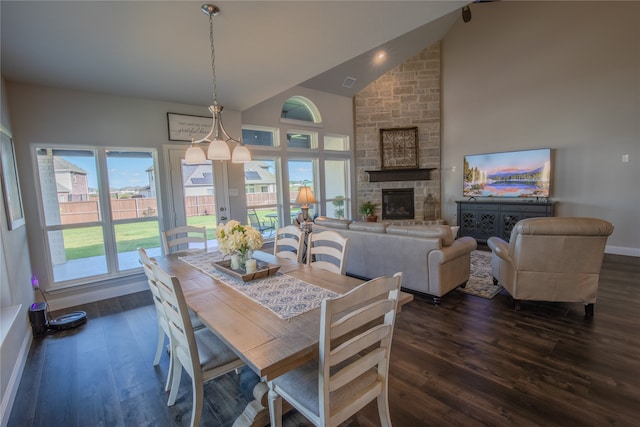 dining area featuring an inviting chandelier, a fireplace, dark hardwood / wood-style flooring, and high vaulted ceiling