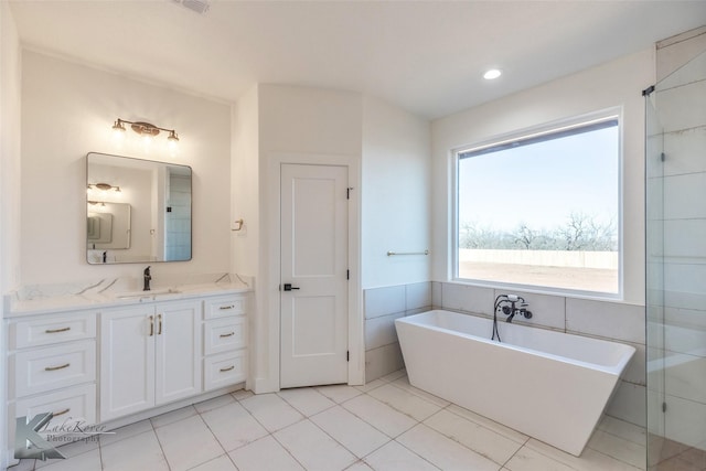 bathroom featuring recessed lighting, a soaking tub, tile patterned flooring, and vanity