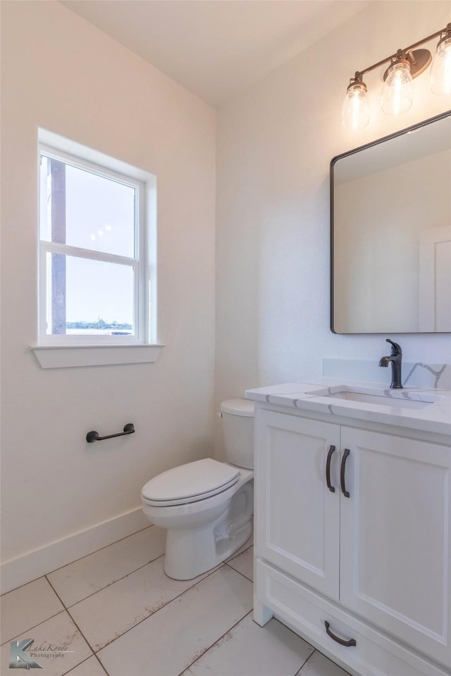 bathroom with toilet, baseboards, and vanity