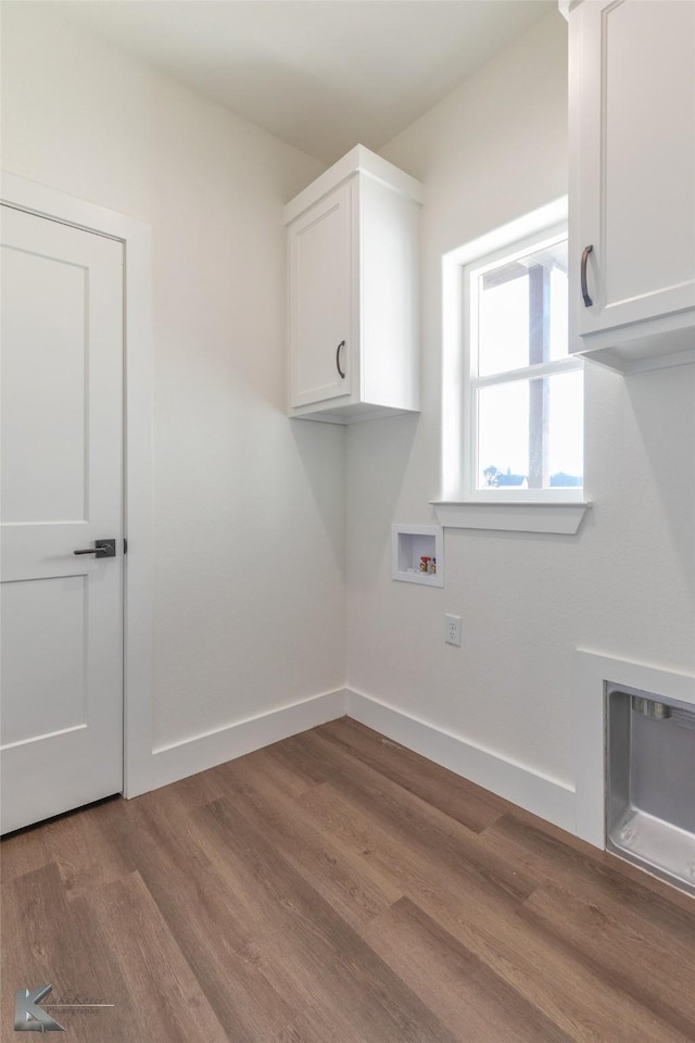 laundry area featuring baseboards, washer hookup, wood finished floors, and cabinet space