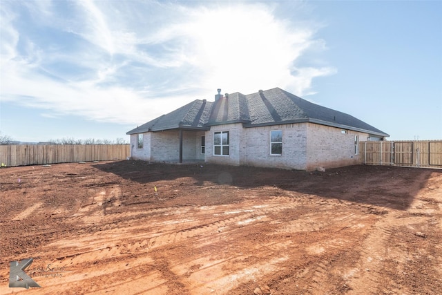 rear view of house with fence and brick siding