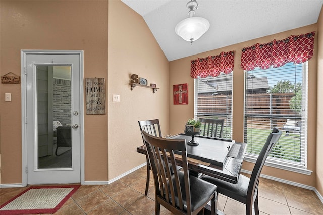 tiled dining area featuring vaulted ceiling and a textured ceiling