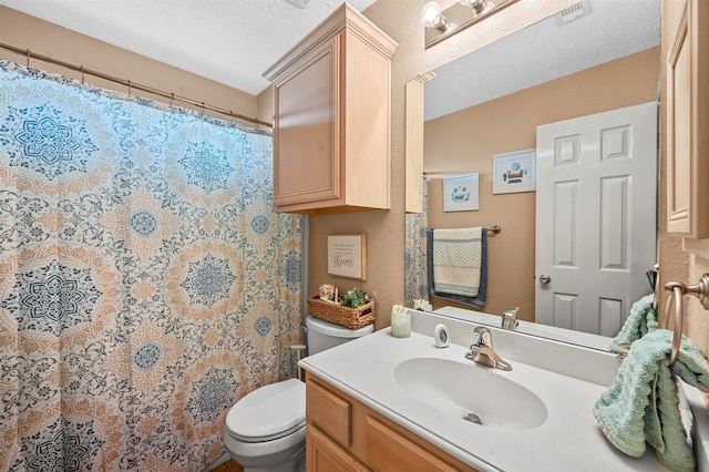 bathroom with vanity, toilet, and a textured ceiling