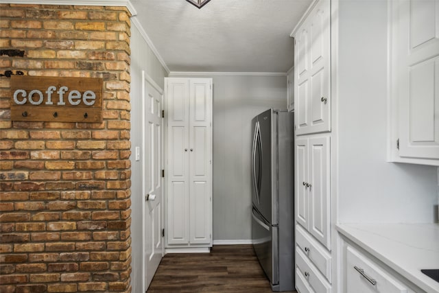 kitchen featuring crown molding, light stone counters, dark hardwood / wood-style flooring, white cabinetry, and stainless steel refrigerator