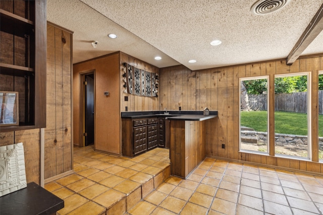 kitchen featuring wood walls, light tile patterned floors, and a textured ceiling