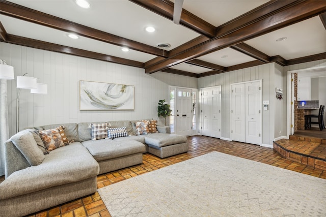 living room with beam ceiling and wood walls