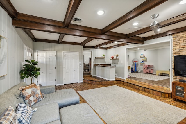 living room with beam ceiling, ceiling fan, and wood walls