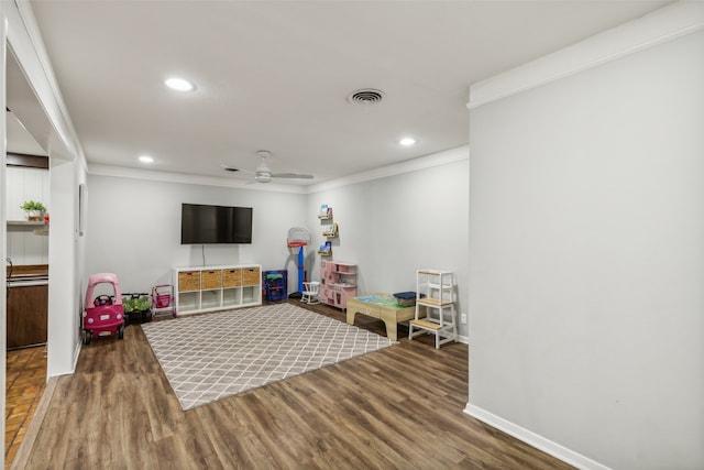 rec room featuring ceiling fan, wood-type flooring, and ornamental molding