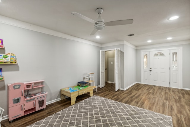 playroom with ceiling fan, dark hardwood / wood-style floors, and ornamental molding