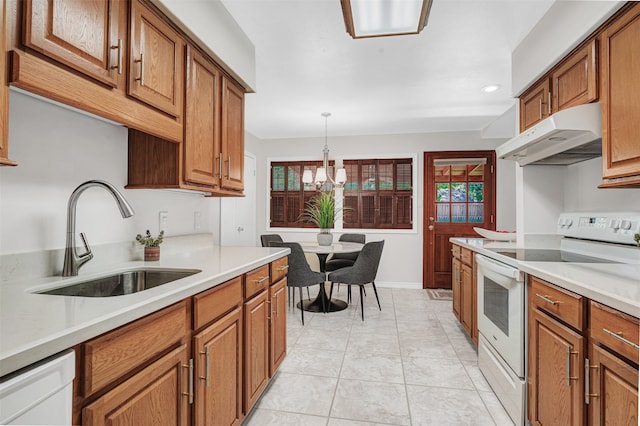 kitchen with light tile patterned flooring, white appliances, decorative light fixtures, sink, and a notable chandelier