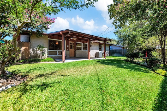 rear view of property featuring a lawn and central AC