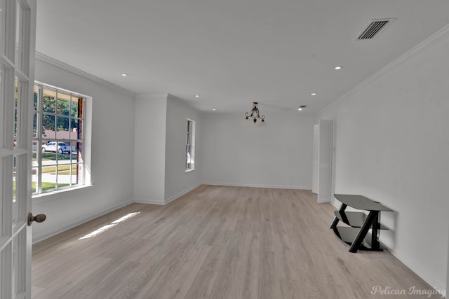 unfurnished living room featuring an inviting chandelier, crown molding, and light wood-type flooring