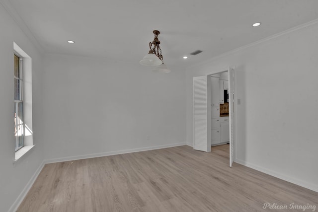 empty room with crown molding and light hardwood / wood-style flooring