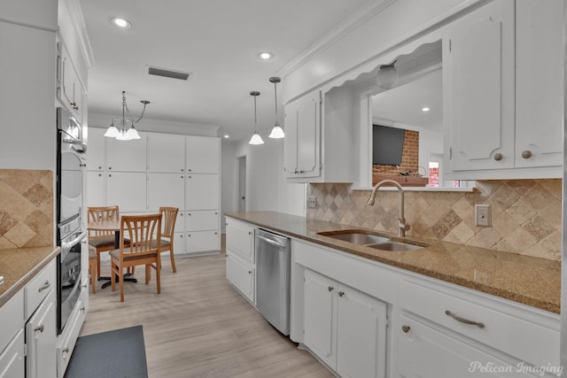 kitchen featuring white cabinets, stainless steel dishwasher, ornamental molding, decorative light fixtures, and sink