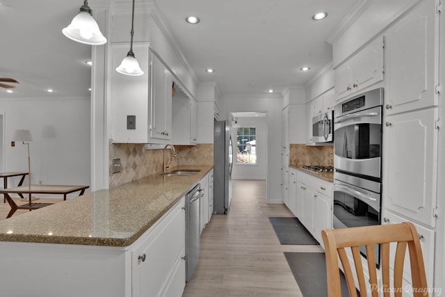 kitchen with appliances with stainless steel finishes, sink, white cabinets, and light wood-type flooring