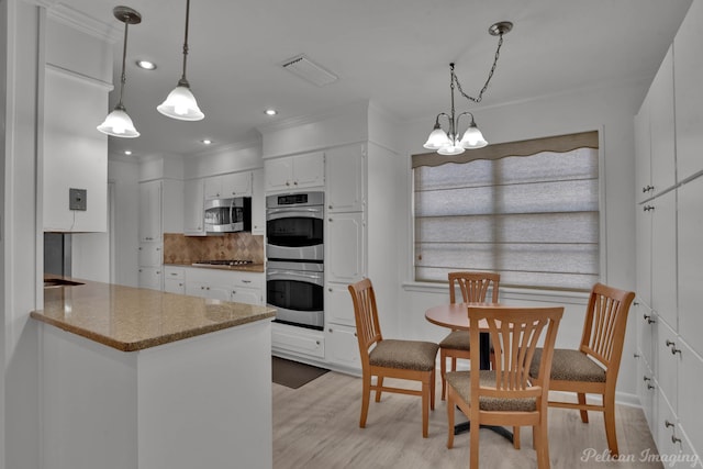 kitchen featuring stainless steel appliances, a notable chandelier, decorative light fixtures, white cabinets, and light hardwood / wood-style floors