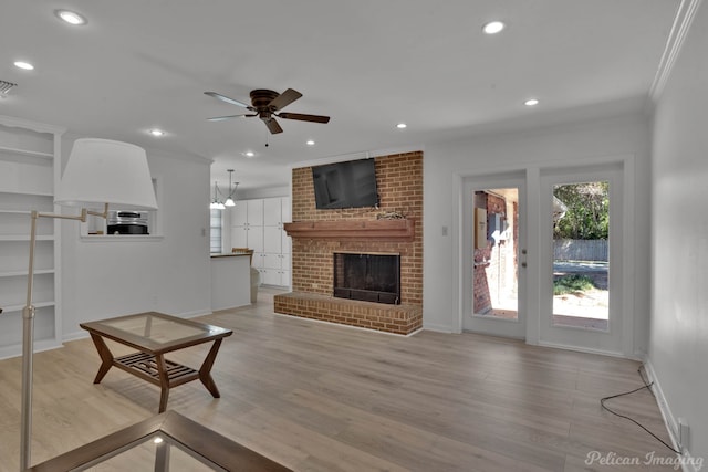 living room with ornamental molding, a brick fireplace, light hardwood / wood-style floors, and ceiling fan