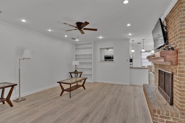 living area with light hardwood / wood-style floors, ornamental molding, a brick fireplace, and ceiling fan