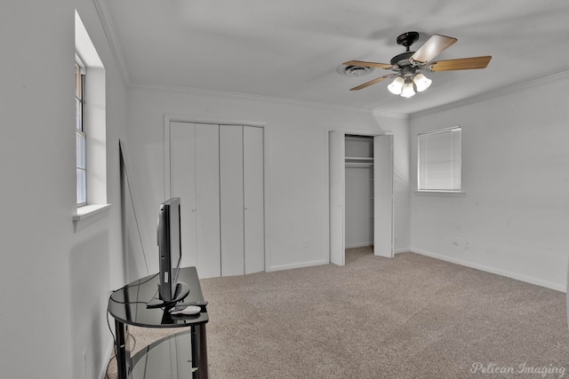 carpeted bedroom with crown molding, multiple closets, and ceiling fan