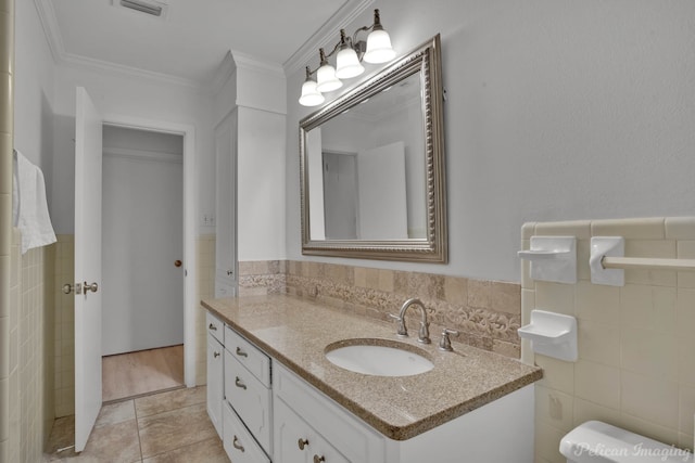 bathroom with toilet, tile walls, vanity, ornamental molding, and tile patterned flooring