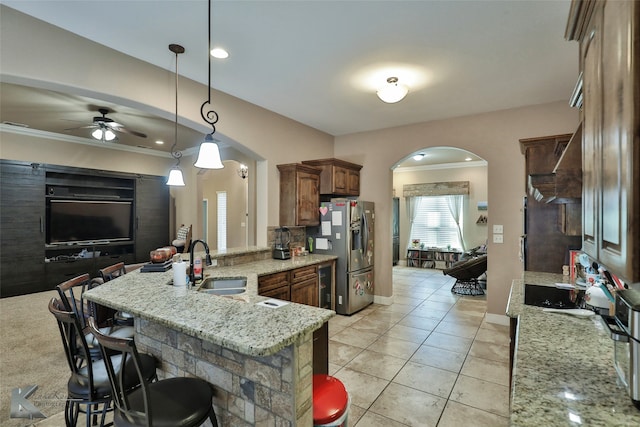 kitchen featuring a kitchen breakfast bar, hanging light fixtures, kitchen peninsula, stainless steel refrigerator with ice dispenser, and sink