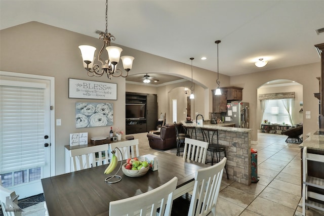 tiled dining area featuring ceiling fan with notable chandelier, ornamental molding, and sink