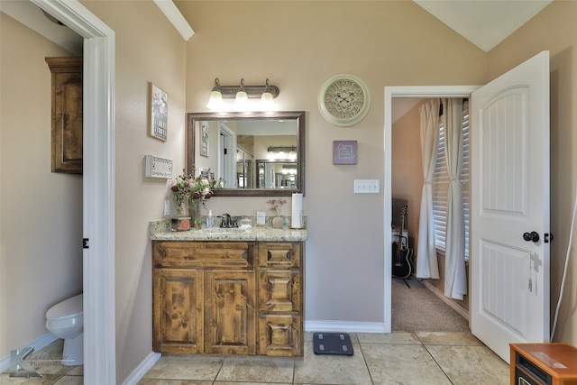 bathroom with tile patterned flooring, vanity, toilet, and vaulted ceiling