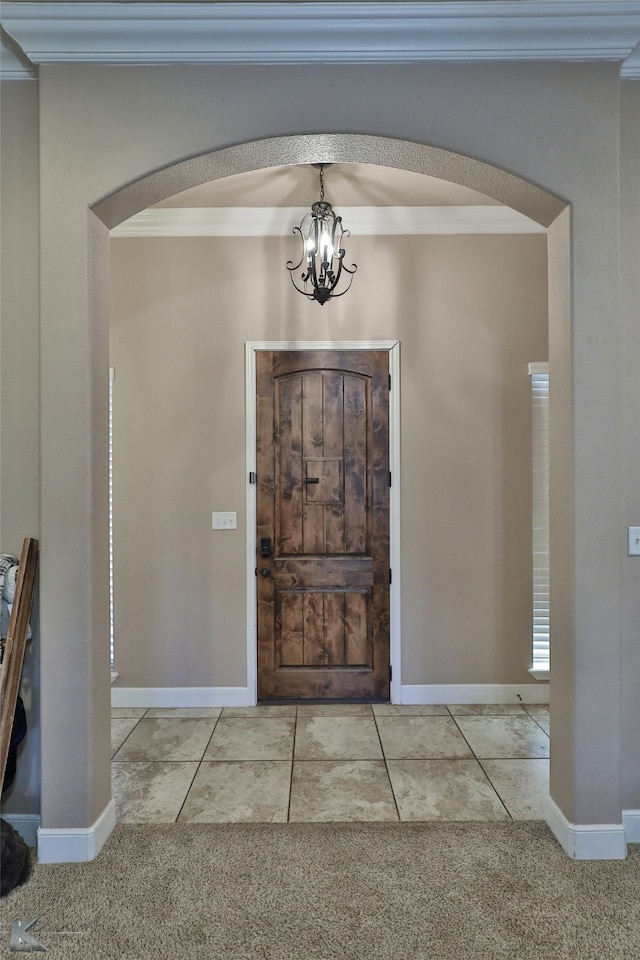 carpeted entrance foyer featuring ornamental molding and a chandelier