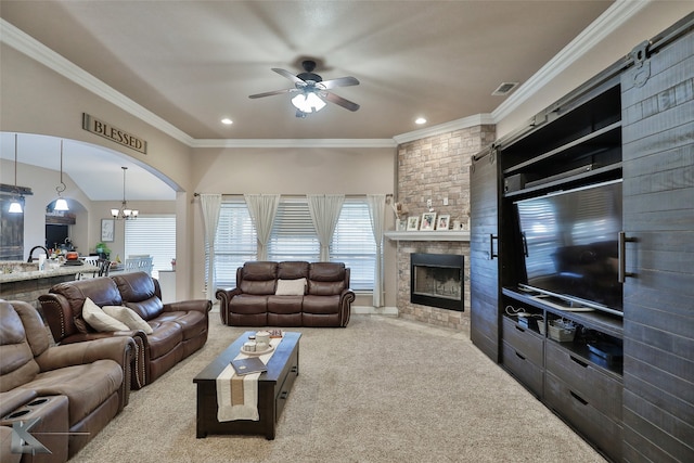 carpeted living room featuring ceiling fan with notable chandelier, a fireplace, and crown molding