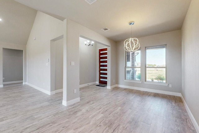 unfurnished room with lofted ceiling, light wood-type flooring, and a chandelier