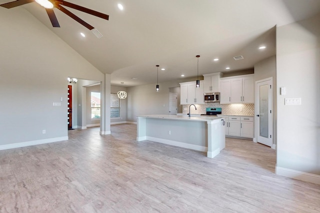 kitchen featuring light hardwood / wood-style floors, an island with sink, white cabinets, appliances with stainless steel finishes, and ceiling fan