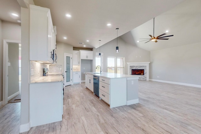 kitchen featuring sink, white cabinetry, a fireplace, a center island with sink, and ceiling fan