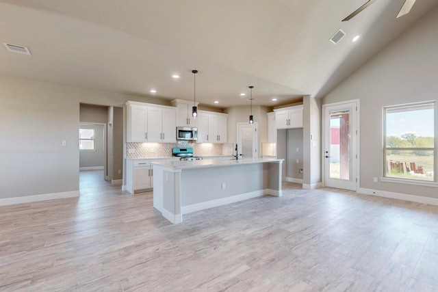 kitchen featuring white cabinets, an island with sink, appliances with stainless steel finishes, and plenty of natural light