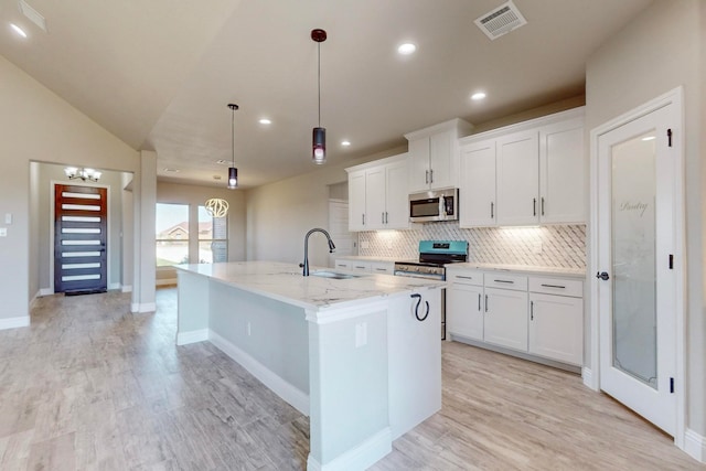 kitchen with an island with sink, sink, decorative light fixtures, white cabinetry, and stainless steel appliances