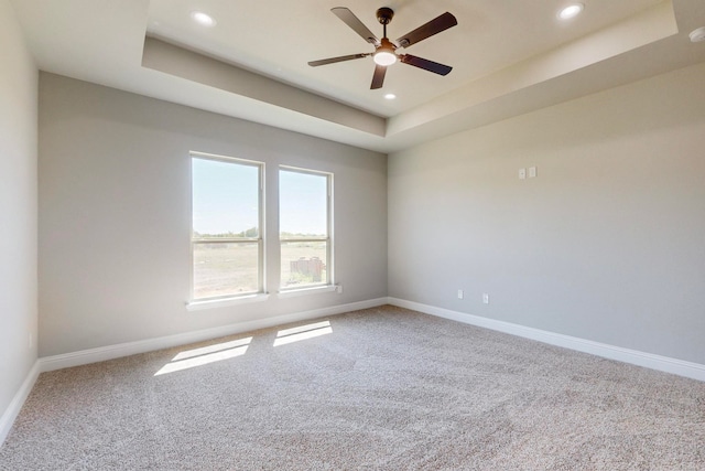 unfurnished room featuring ceiling fan, a raised ceiling, and carpet flooring